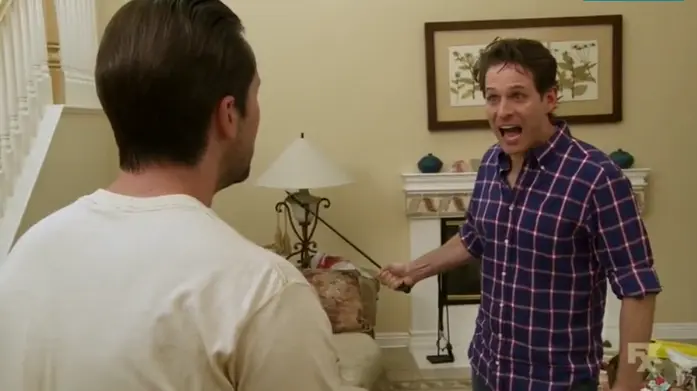 A freezeframe from Always Sunny in Philadelphia, where Dennis is holding a stick and screaming wide-eyed at Mac.